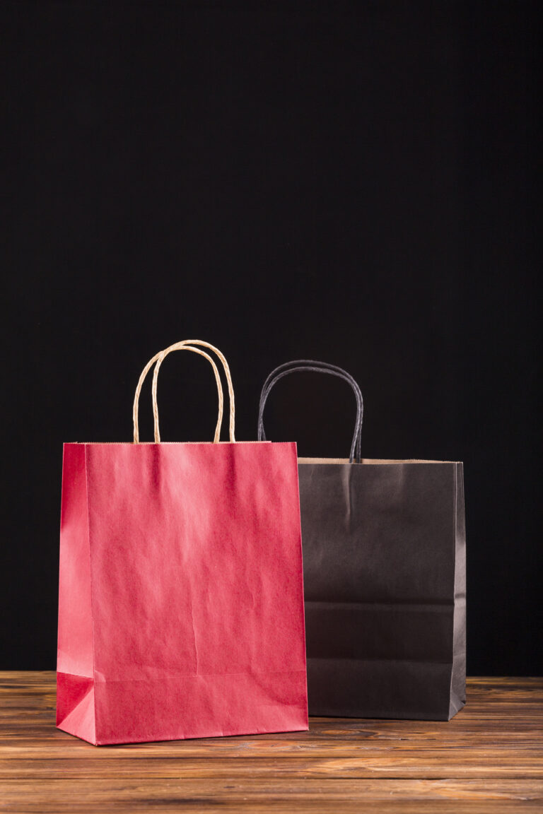 red-black-paper-bag-wooden-surface-against-black-backdrop